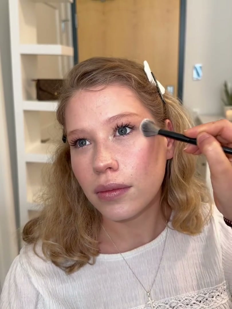 A client mid-application, a makeup brush at her eye